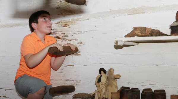 A boy climbs a peg staircase inside the cabin at the Living Historical Farm at Lincoln Boyhood National Memorial