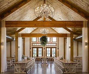 View of exposed beams, chandelier, and seating inside of Matilda's Event Barn