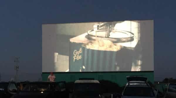 Image of popcorn on a drive-in movie screen with cars in the foreground