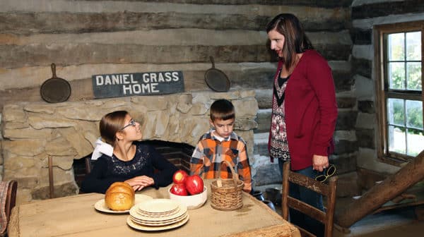 Mother and two kids inside cabin at Lincoln Pioneer Village & Museum