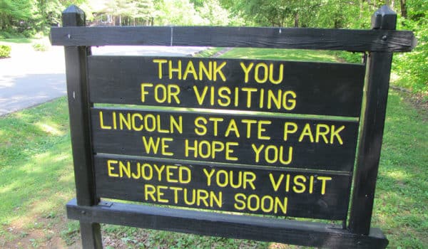 Dark wood sign on side of road reads thank you for visiting Lincoln State Park, we hope you enjoyed your visit, return soon