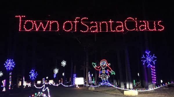 A lighted display that reads "Town of Santa Claus" hangs above the entrance to more lighted displays at the Santa Claus Land of Lights