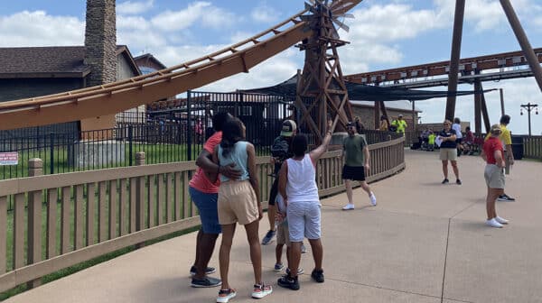 Family of four points toward the Thunderbird roller coaster at Holiday World as a cameraman films them for a destination video