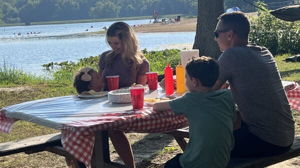 Family of four sits at picnic table alongside Lake Lincoln at Lincoln State Park during destination video shoot