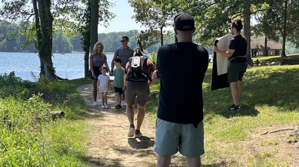 Family of four walks on trail by Lake Lincoln at Lincoln State Park as a camera crew films them for a destination video