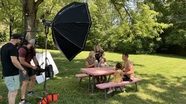 Family of four enjoys frozen hot chocolate at a picnic table behind Santa's Candy Castle as a crew films them for a destination video