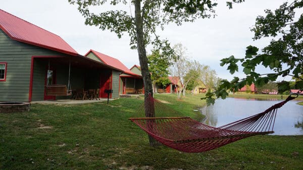 Cabins and a red hammock at Santa's Lakeside Cottages are shown alongside a lake 