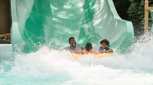 A man and two boys in a yellow inner tube come off a water slide at Holiday World & Splashin' Safari