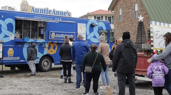 People stand in line in front of the Auntie Anne's Pretzels truck during the Santa Claus Christmas Celebration