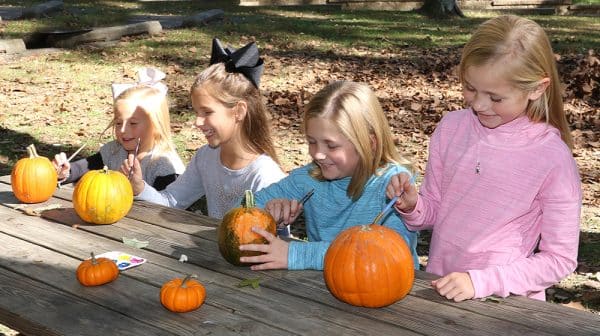 Four young girls sit at a picnic table at Lincoln State Park and paint pumpkins