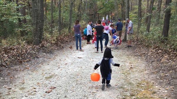 Small child in Batman costume runs to catch up to the crowd on the trails at the Yellig Trick-or-Treat Trail
