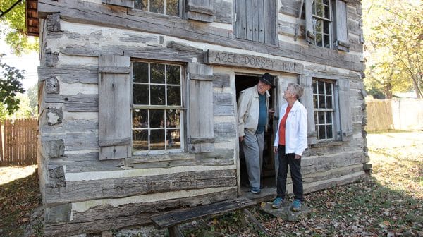 Senior man and woman exit a cabin at Lincoln Pioneer Village & Museum