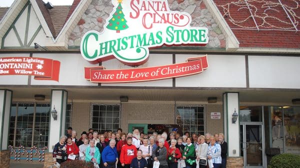 Large group stands poses for a photo outside the Santa Claus Christmas Store