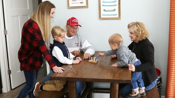 Grandparents, daughter, and two grandsons play a game at a table inside a cabin at Lincoln Pines Lakefront Resort