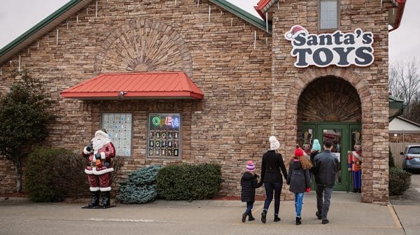 A family in winter coats and hats walks to the entrance of Santa's Toys